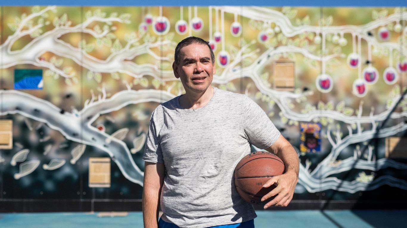 Brightwater Oats Street_disability client with unique graffiti art wall behind him with basketball in hand