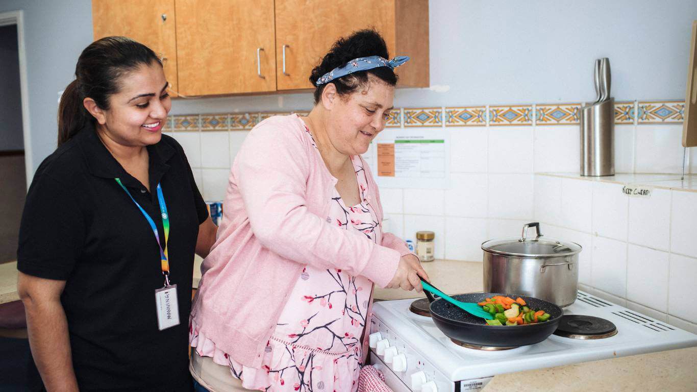 Brightwater Dietitian Services_support worker helping disability client cook on vegetables on the stove for a stirfry