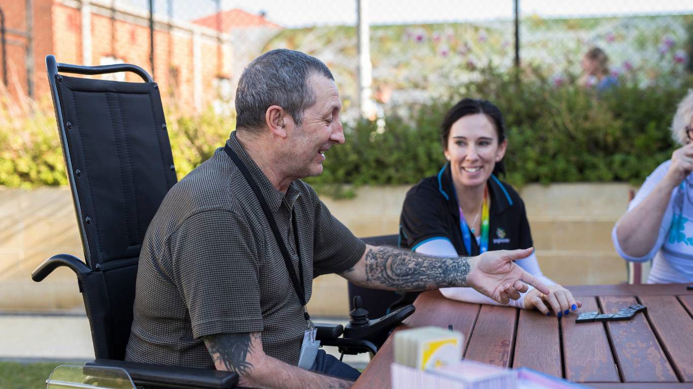 Brightwater Oats Street_disability clients playing dominoes together chatting outside at table